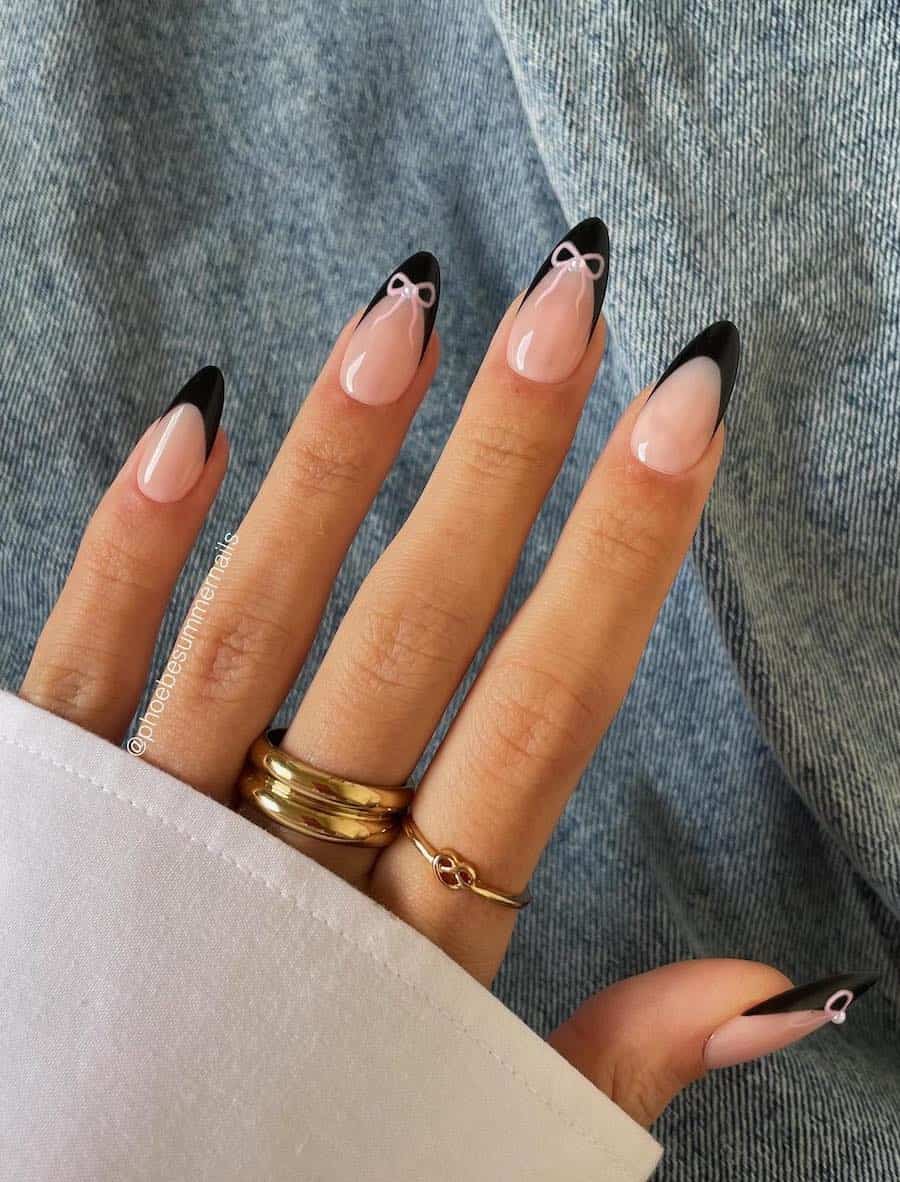medium almond nails with black tips and pink bow accents with pearl centers