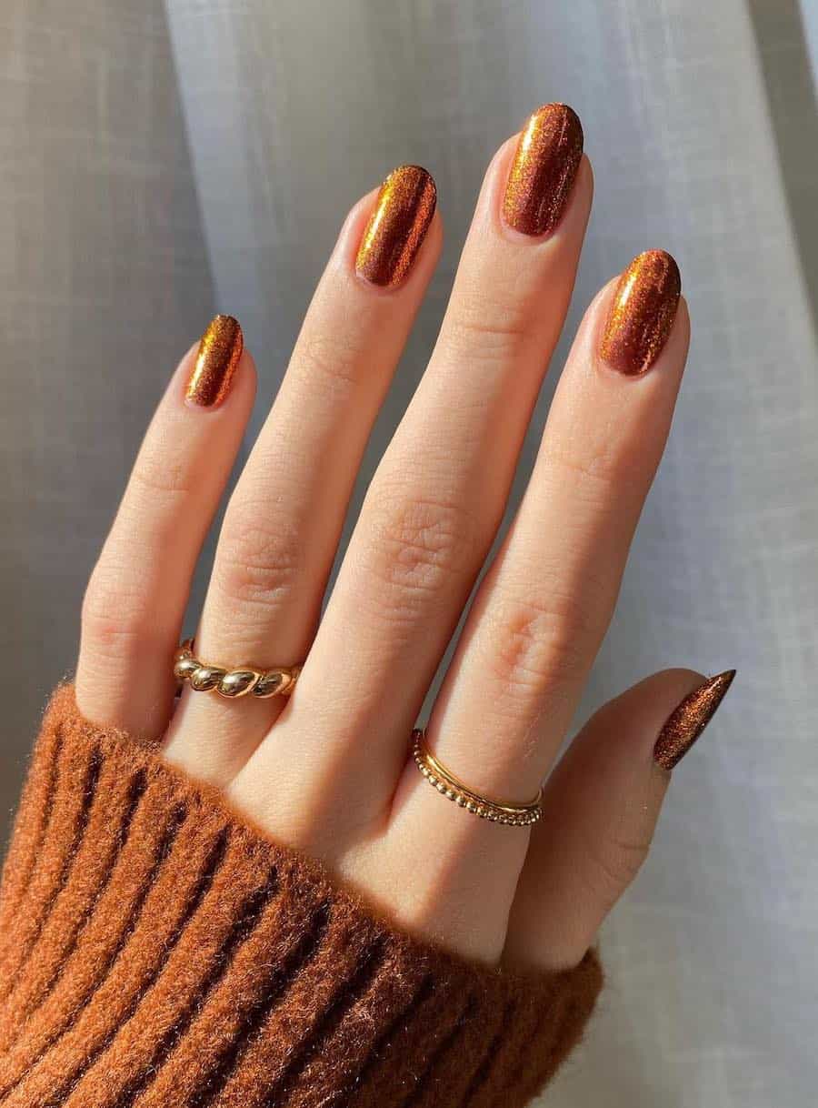 short round nails featuring shimmering copper colored nail polish