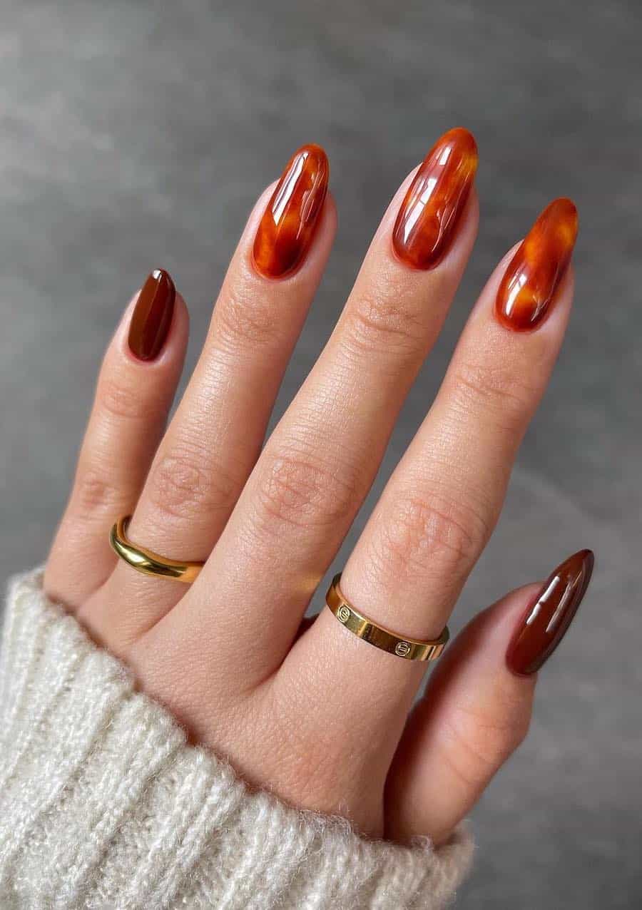 medium almond nails with a red and orange tortoise shell print and brown accent nails
