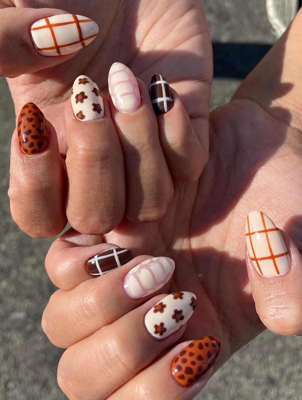 short almond collage nails with burnt orange, cream, and brown polish featuring floral designs, plaid, and animal print
