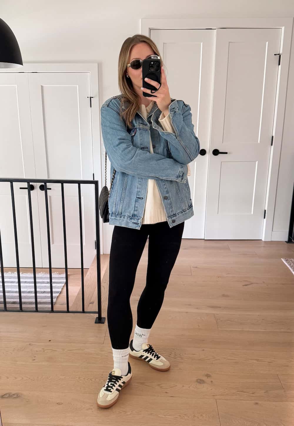 Christal wearing leggings with a white sweater and a denim jacket with sneakers.