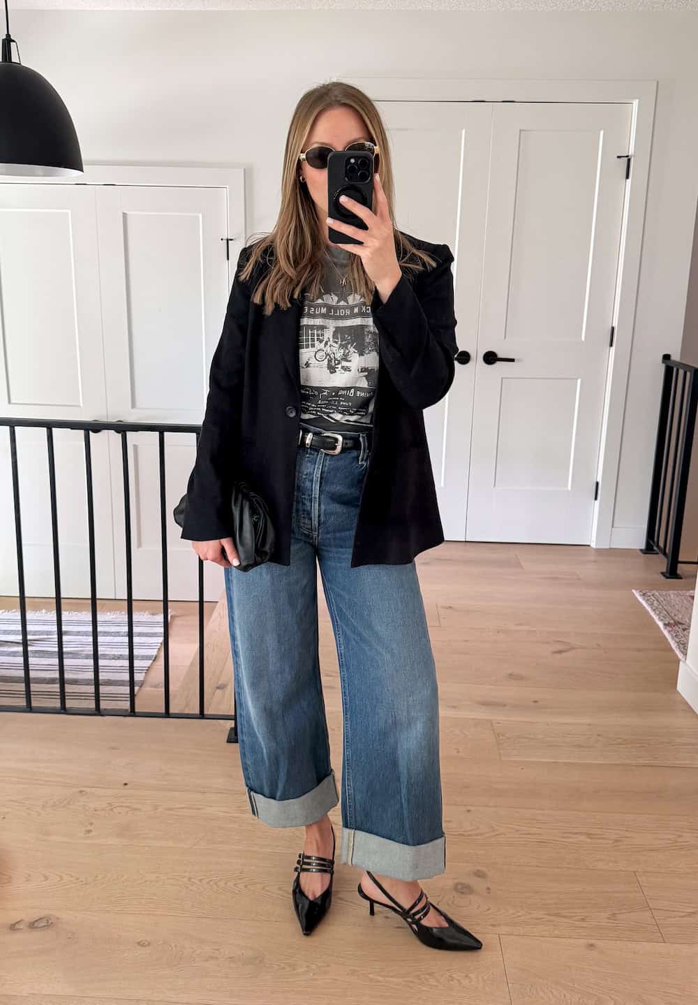 Christal wearing wide-leg jeans with a graphic tee, a black blazer and strappy pointed toe kitten heels.