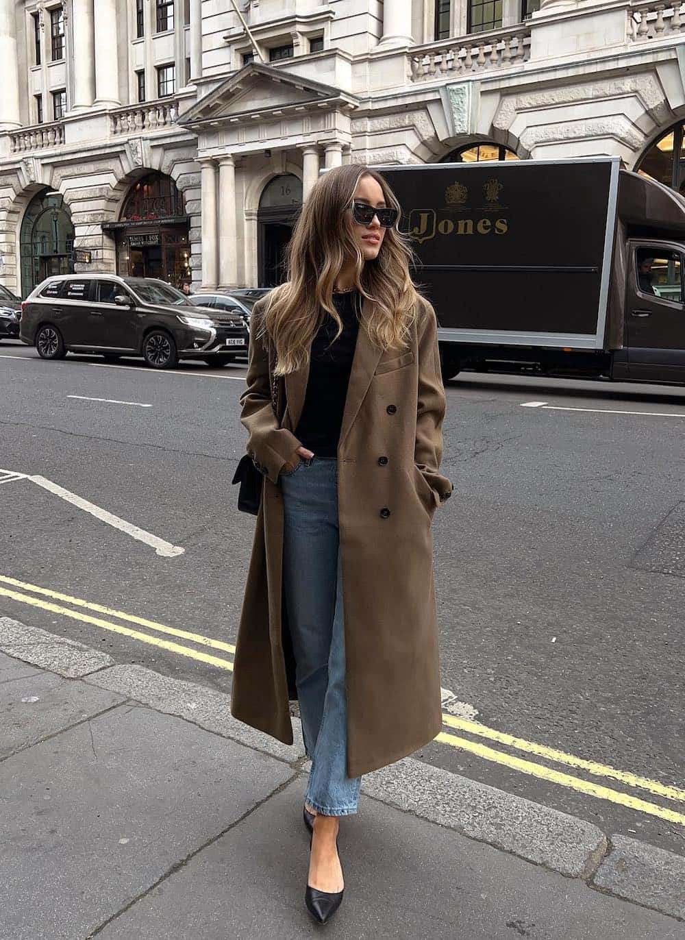 woman wearing a long brown trench coat with jeans and black heels
