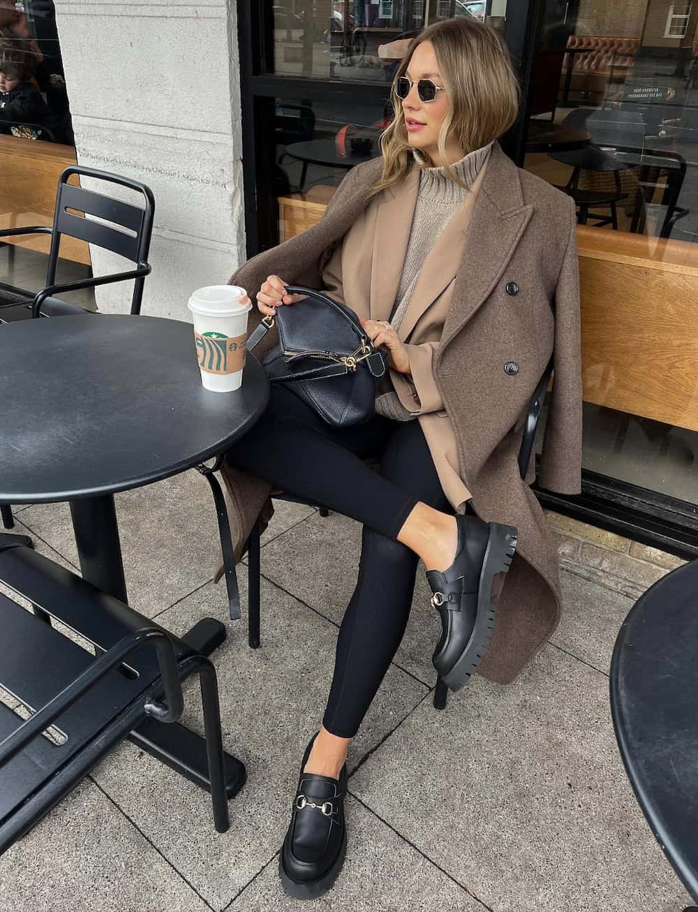 woman wearing an expensive-looking fall outfit with a long coat, turtleneck, black leggings, and black loafers