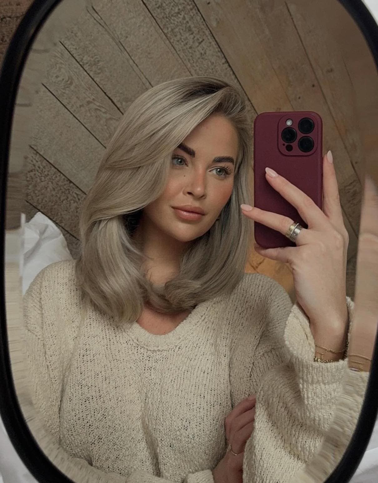 Woman taking a selfie in the mirror showing off her new blonde blowout and color.