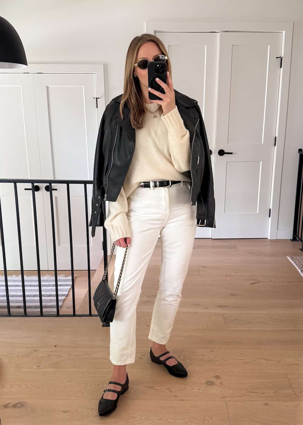 Christal wearing white jeans, a cream sweater and a black leather jacket with black mary jane flats.