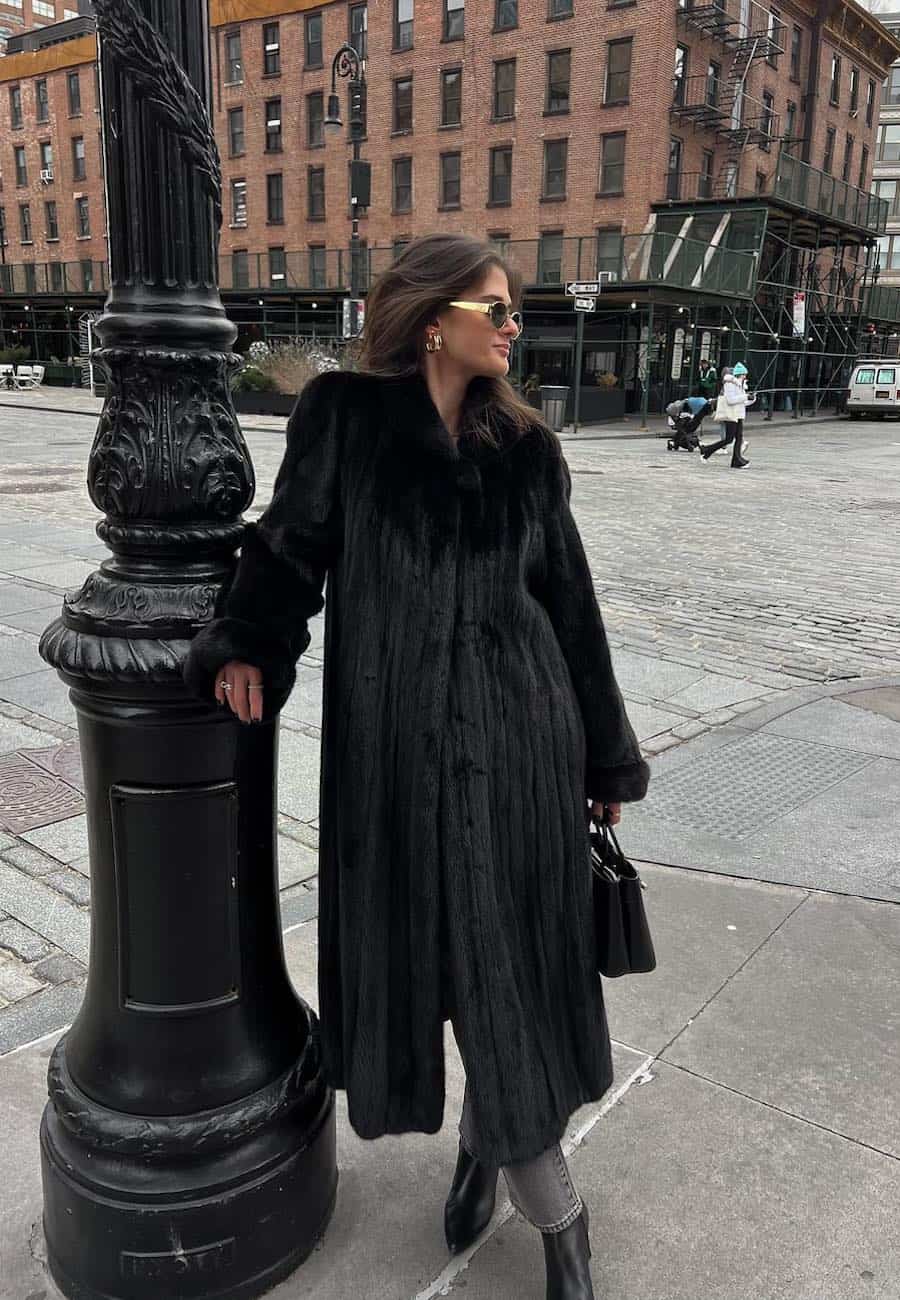 Woman wearing jeans, booties and a full length faux fur coat.