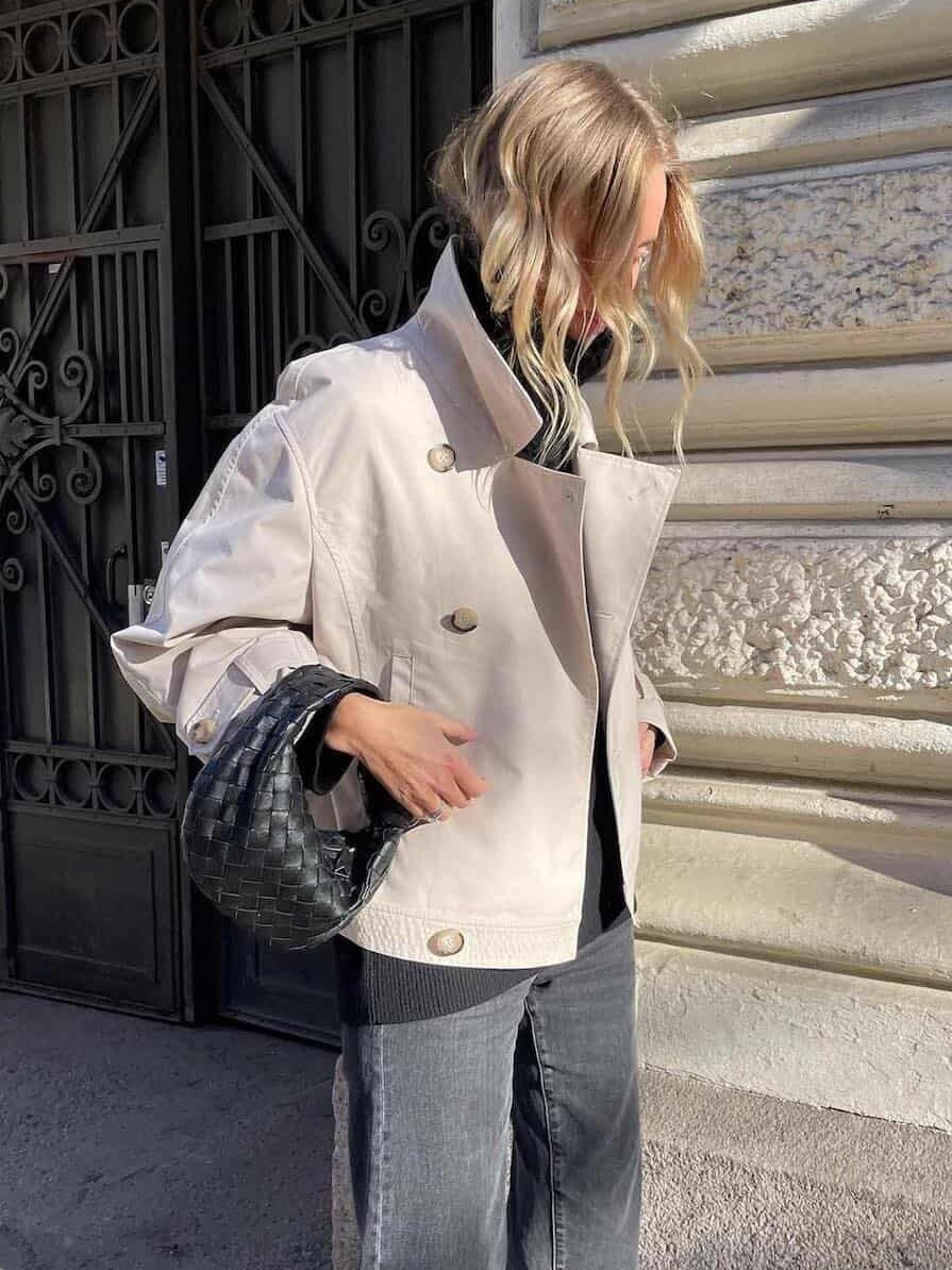 Woman wearing jeans with a cropped trench coat.