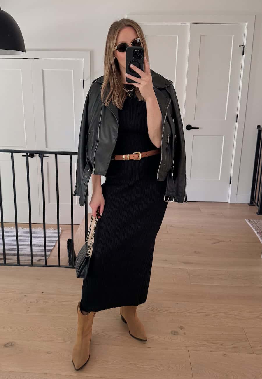 Christal wearing a black midi dress with tan western style boots and a leather jacket.