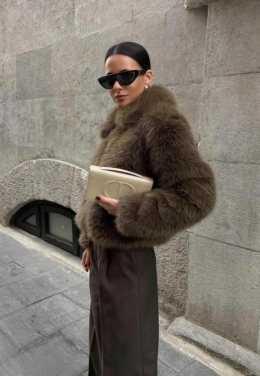 Woman wearing brown trousers with a brown fur coat.