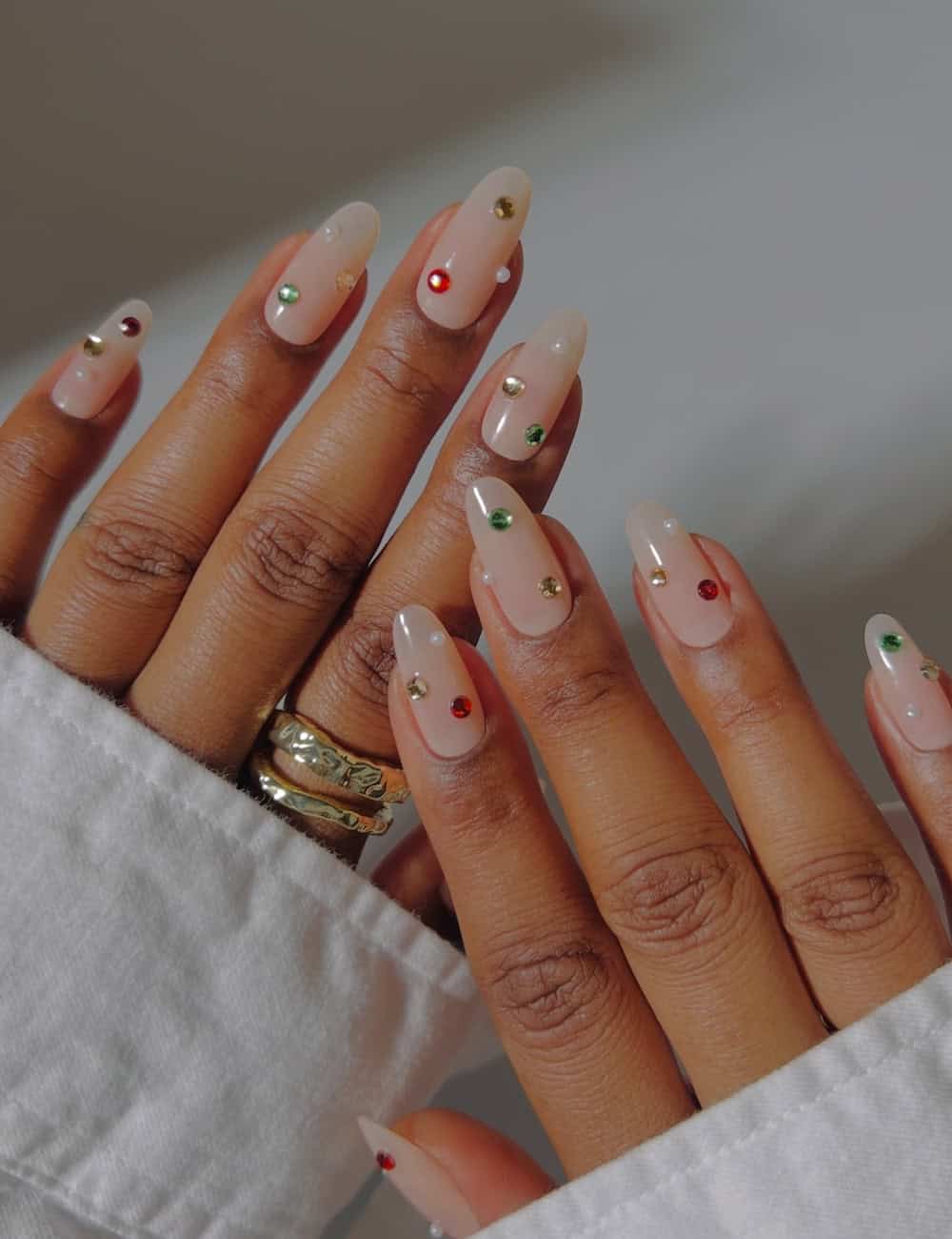 long round milky white nails with gem and pearl embellishments
