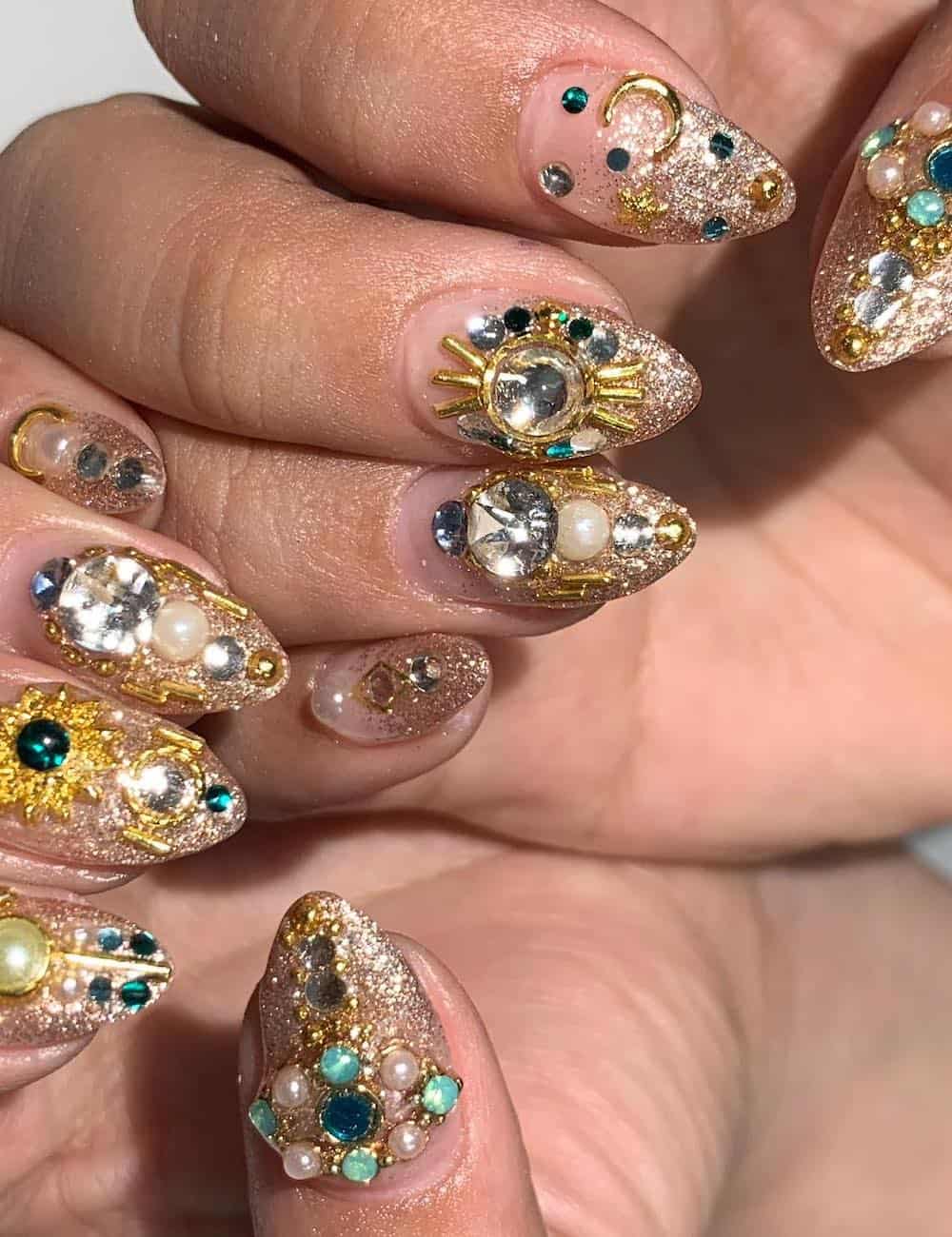 medium almond nails with a glitter ombre and gem and metallic embellishments