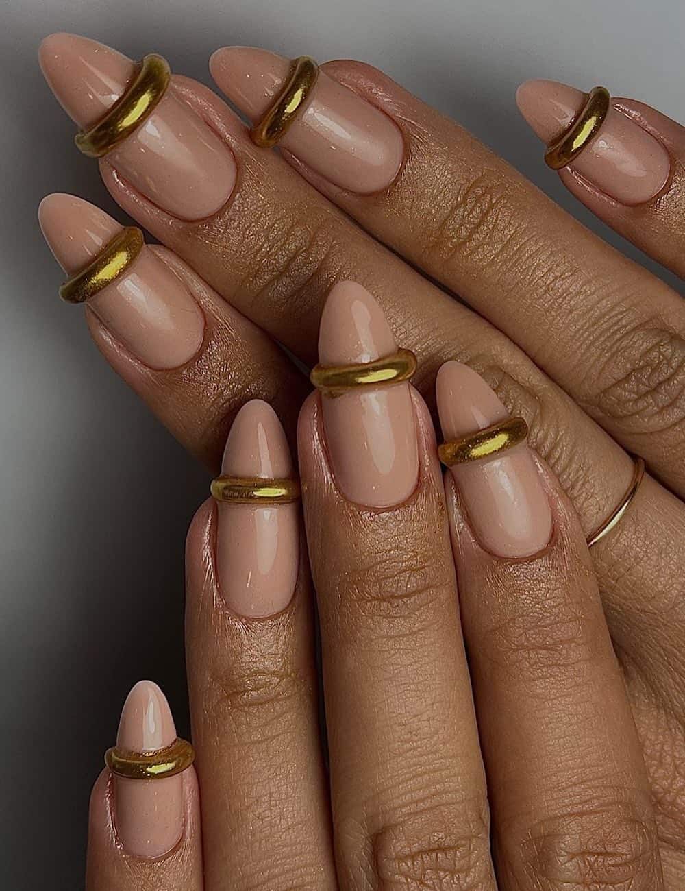 long nude almond nails with 3D gold bands