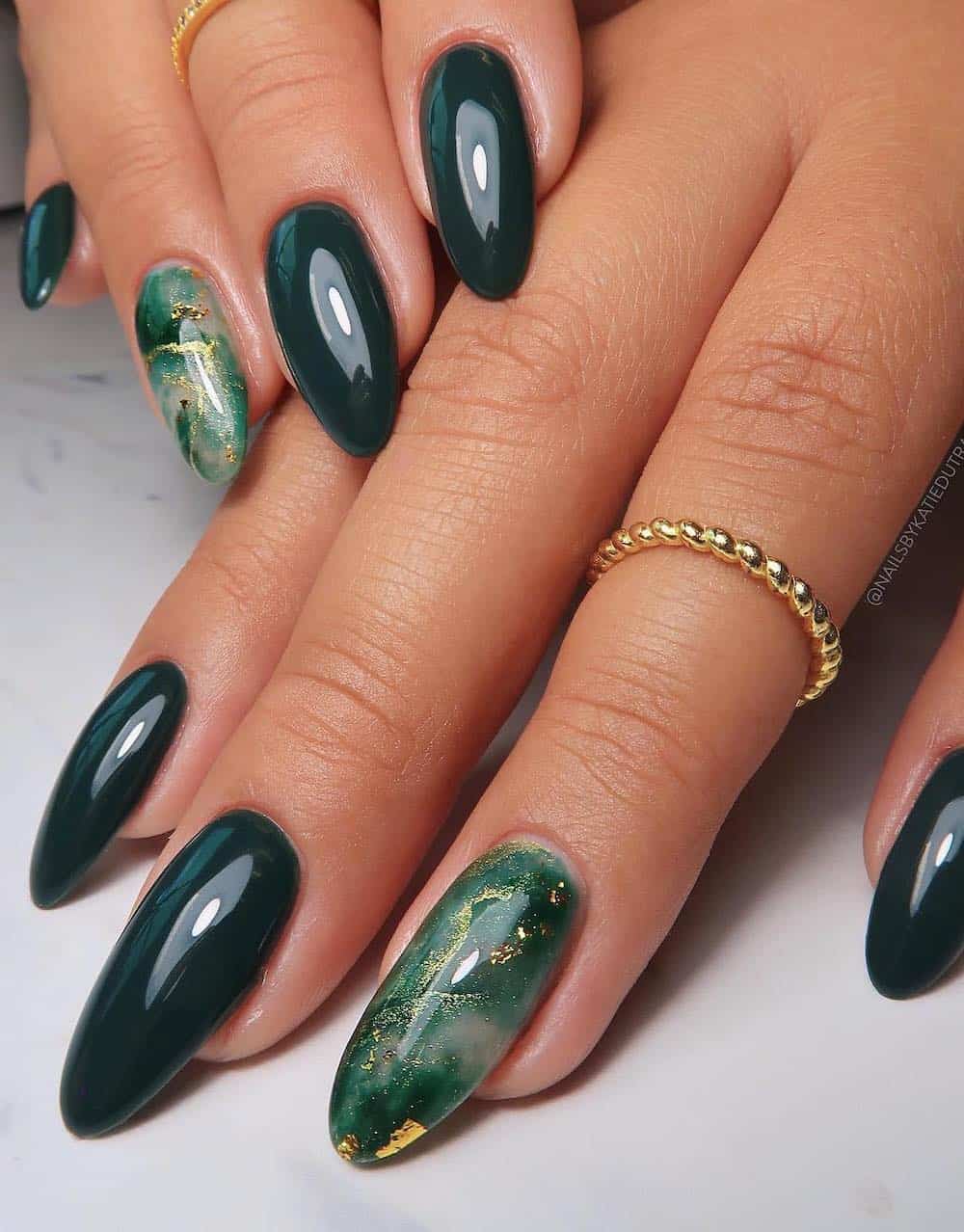 long almond nails with forest green nail polish and marbled accent nails with gold details