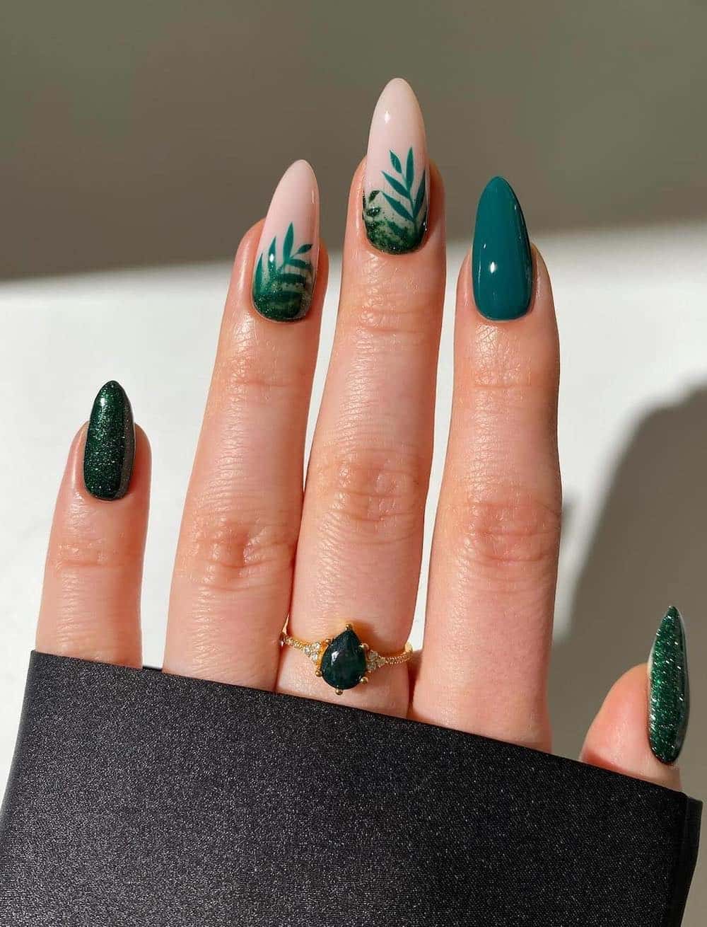long forest green almond nails with milky nude accent nails featuring botanical art and glitter accent nails