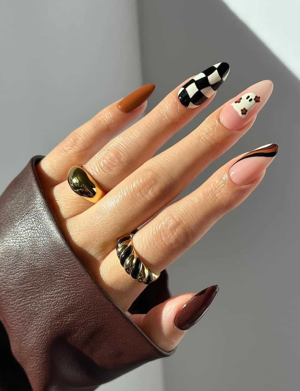 long almond nails featuring brown nail polish, ghost nail art, and checkerboard details