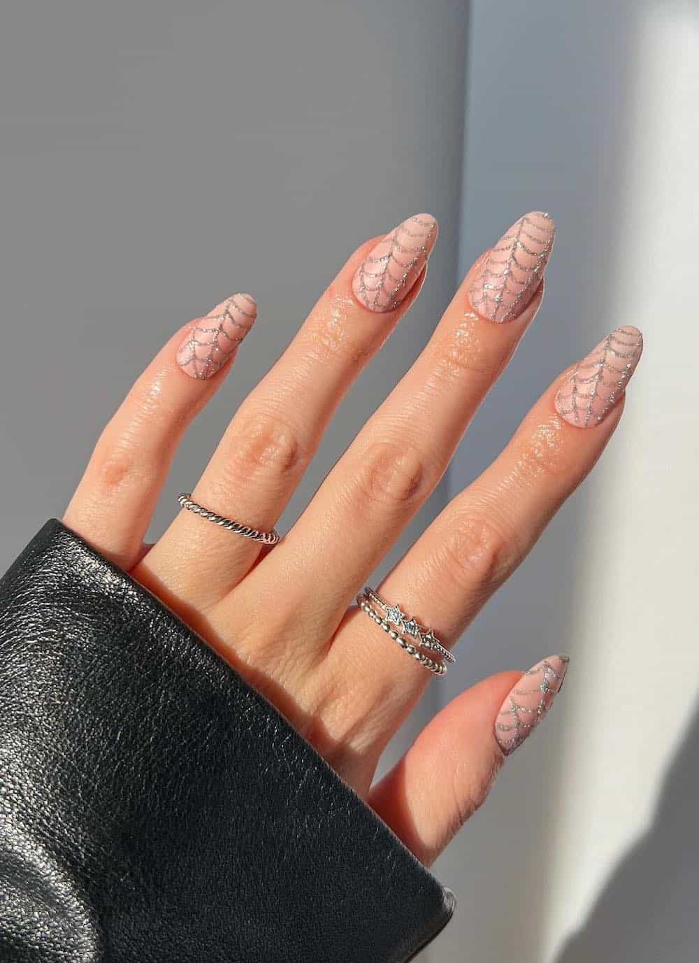 medium nude round nails with silver glitter spider webs