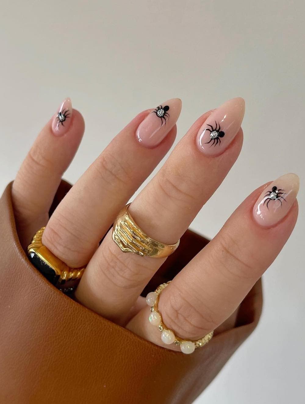 short nude almond nails with black and silver spiders