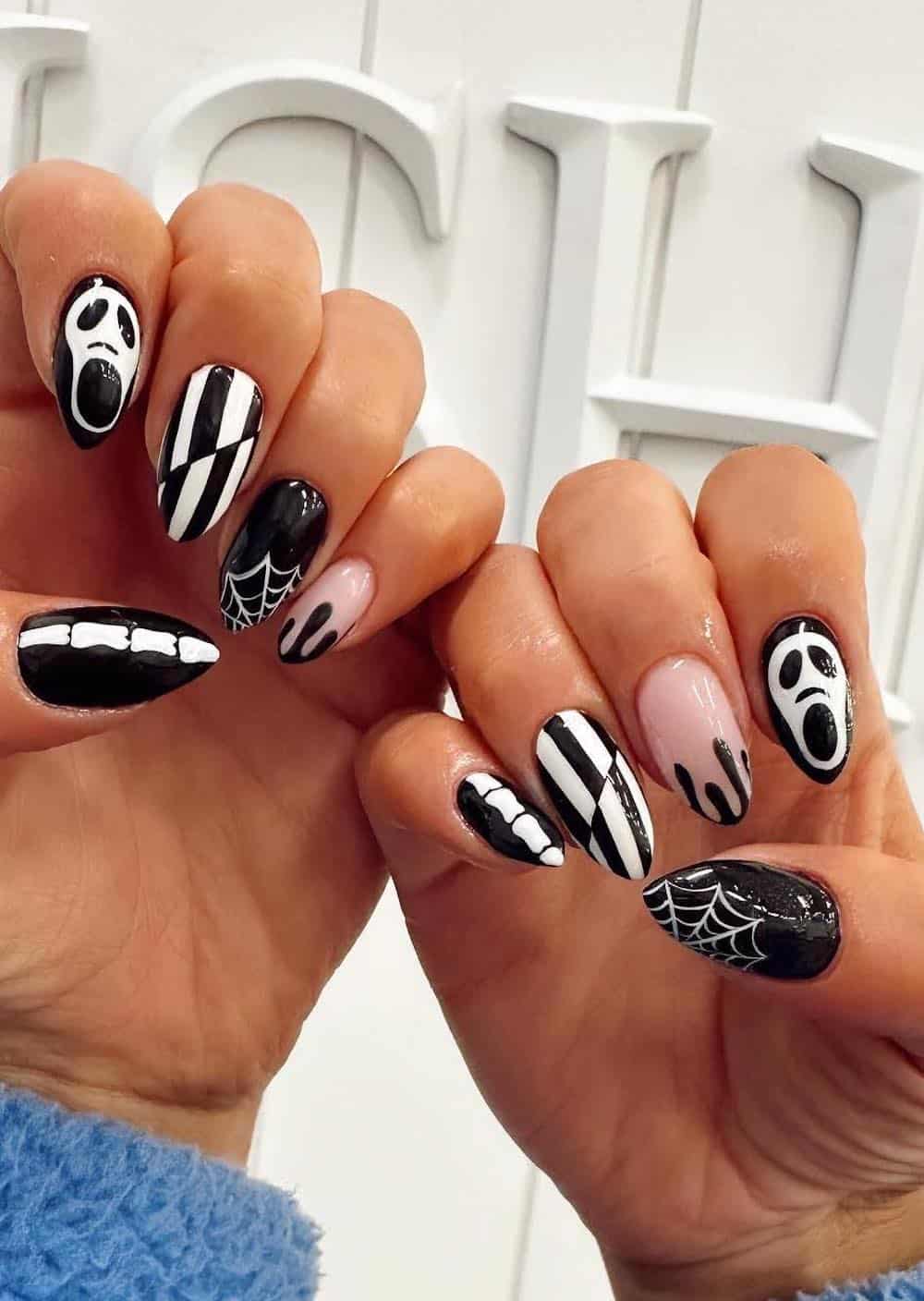 long black and white nails with Halloween nail art like Ghostface, spider webs, and bones