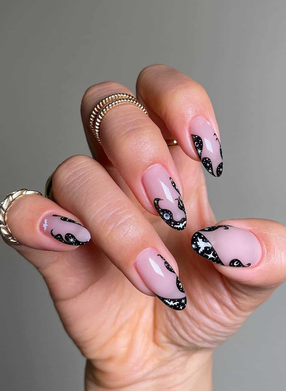 long nude almond nails with swirling black tips and mystical nail art