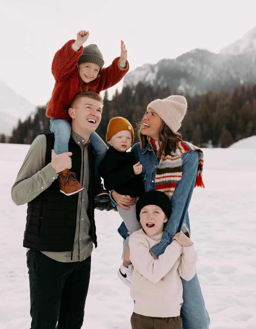a winter family photo with outfits featuring bright tones, denim, beanies, and knit pieces