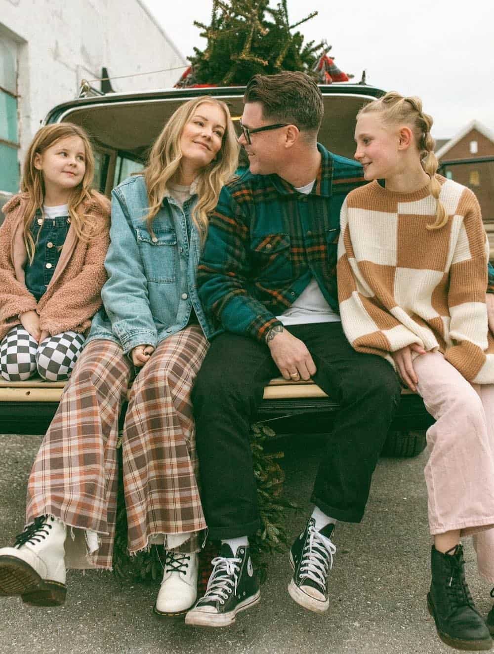 a winter family photoshoot with outfits featuring plaid, checkerboard, flannel, and other retro-inspired styles