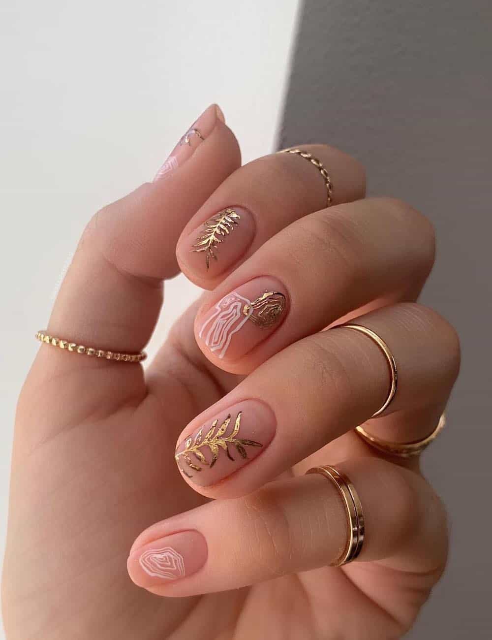 short nude nails with gold leaf botanical art and white geode patterns