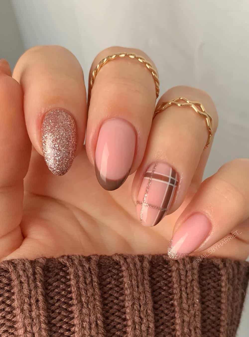 nude almond nails with plaid print, glitter polish, and french tips