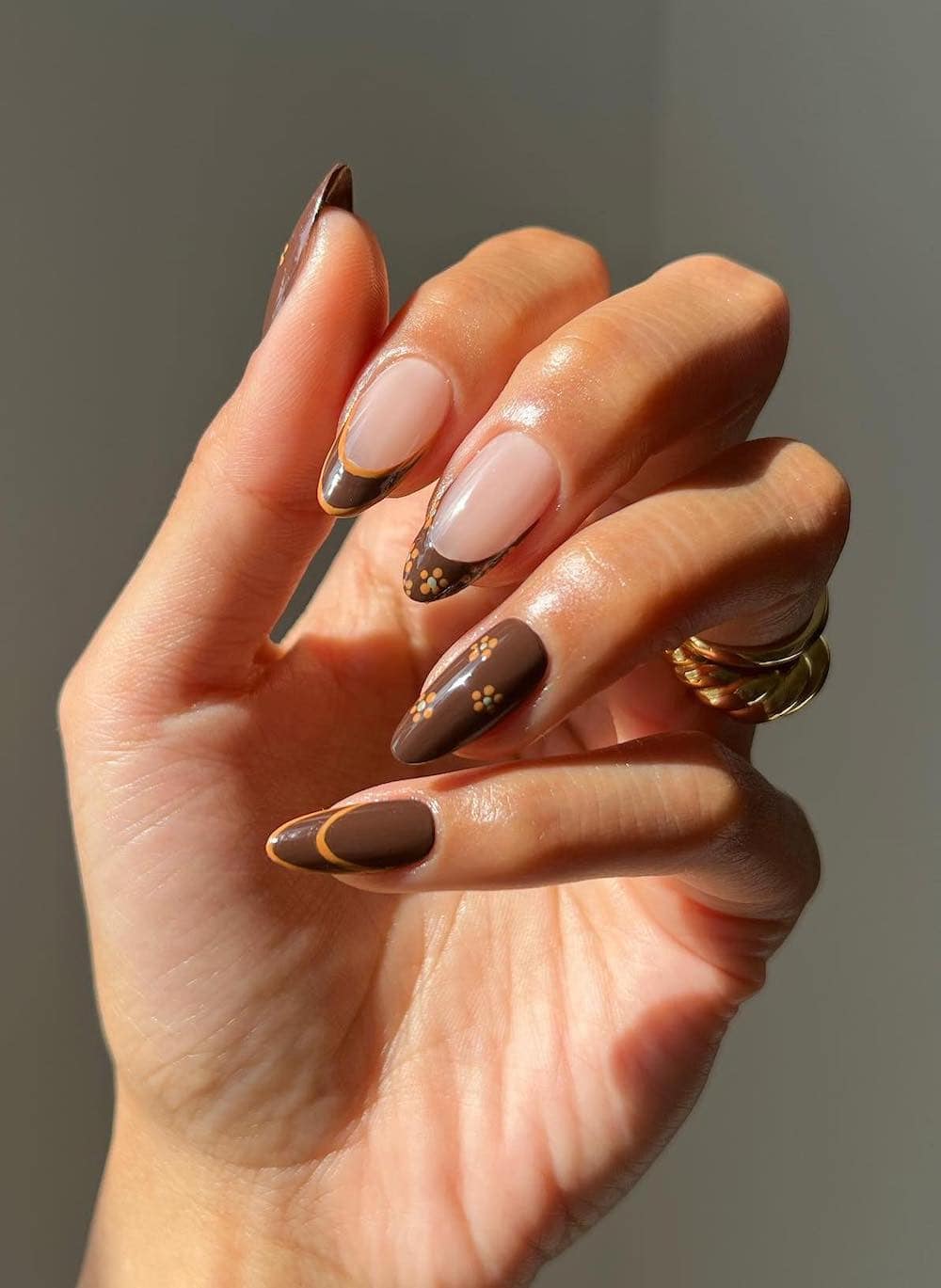 long almond nails with brown nails polish, orange accents, and floral art