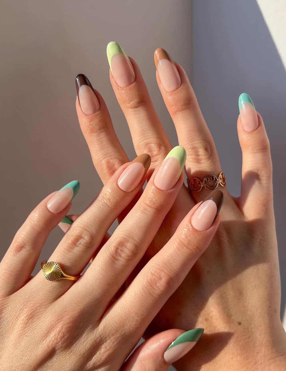 nude almond nails with light blue, light green, brown, and camel tips