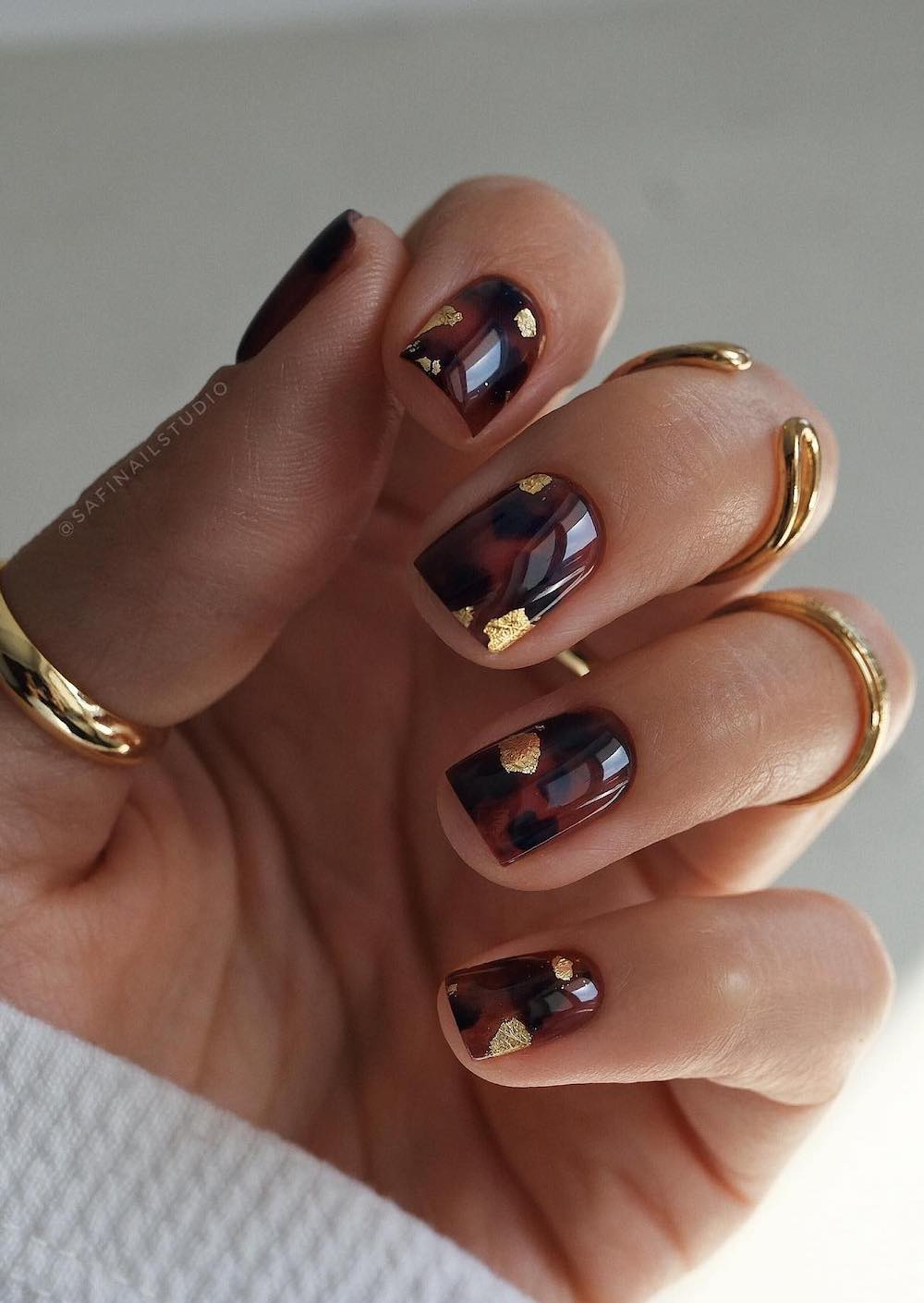 short glossy nails with brown and black tortoise shell print and gold foil