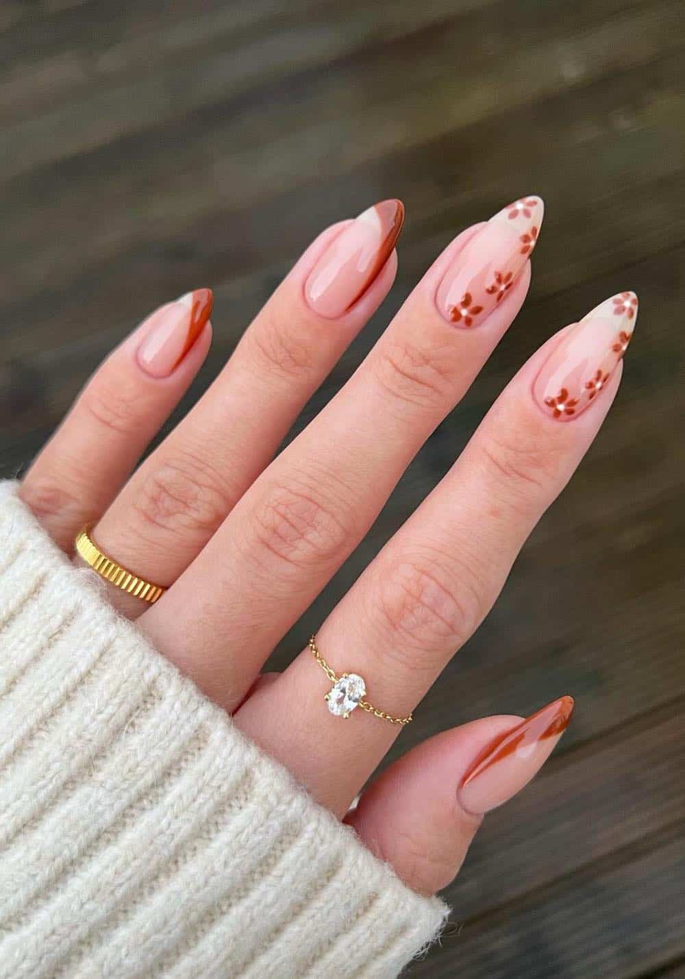 nude almond nails with slanted brown tips and floral nail art