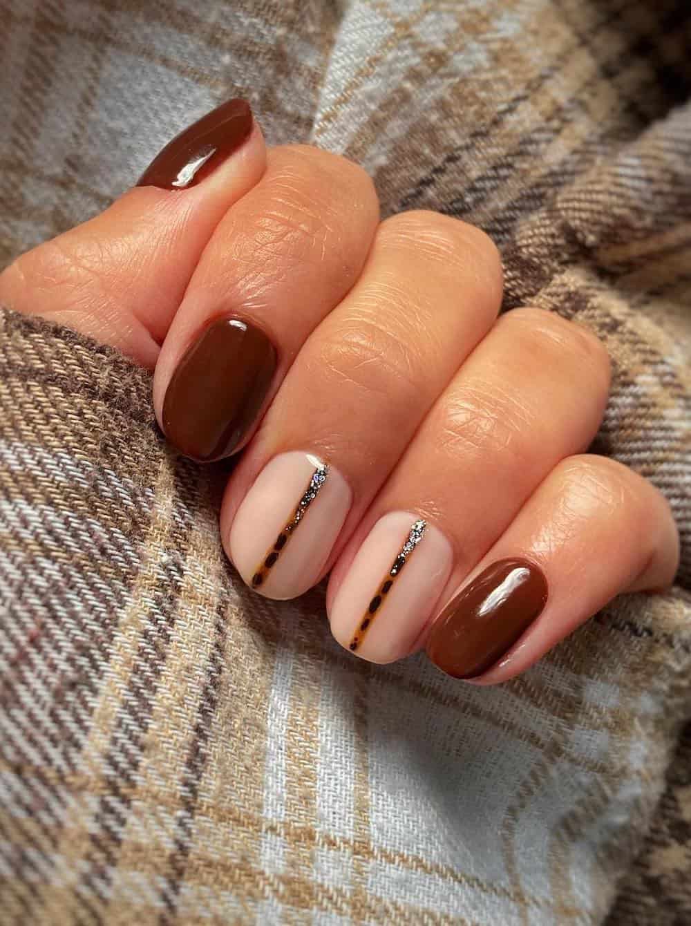 short fall nails with nude and brown polish and patterned accents