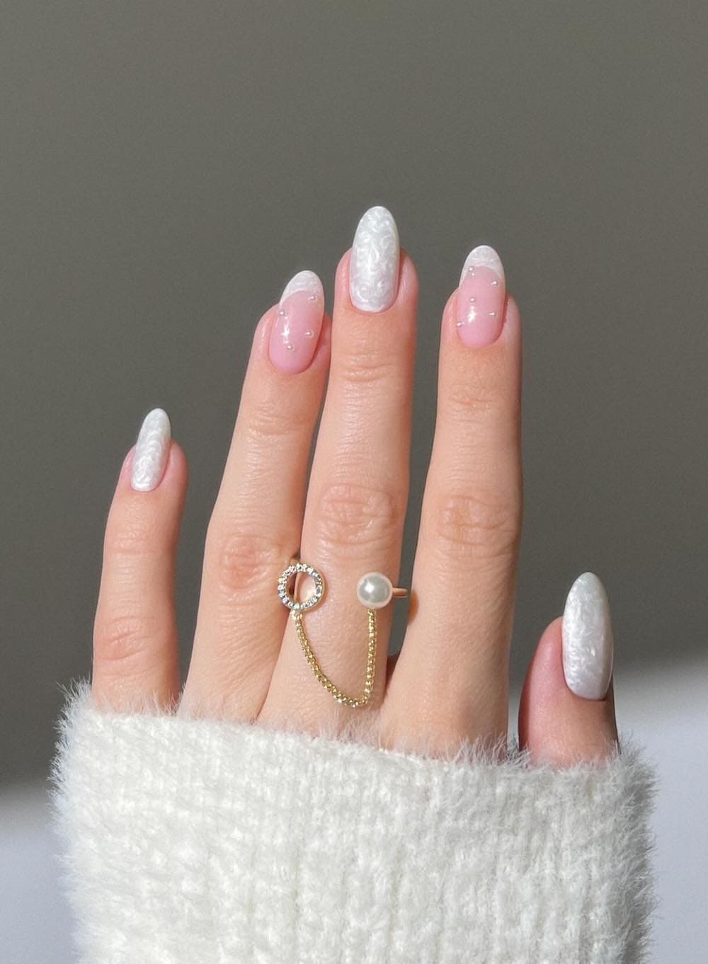 swirling white pearly nails with two french tip accent nails and pearl embellishments