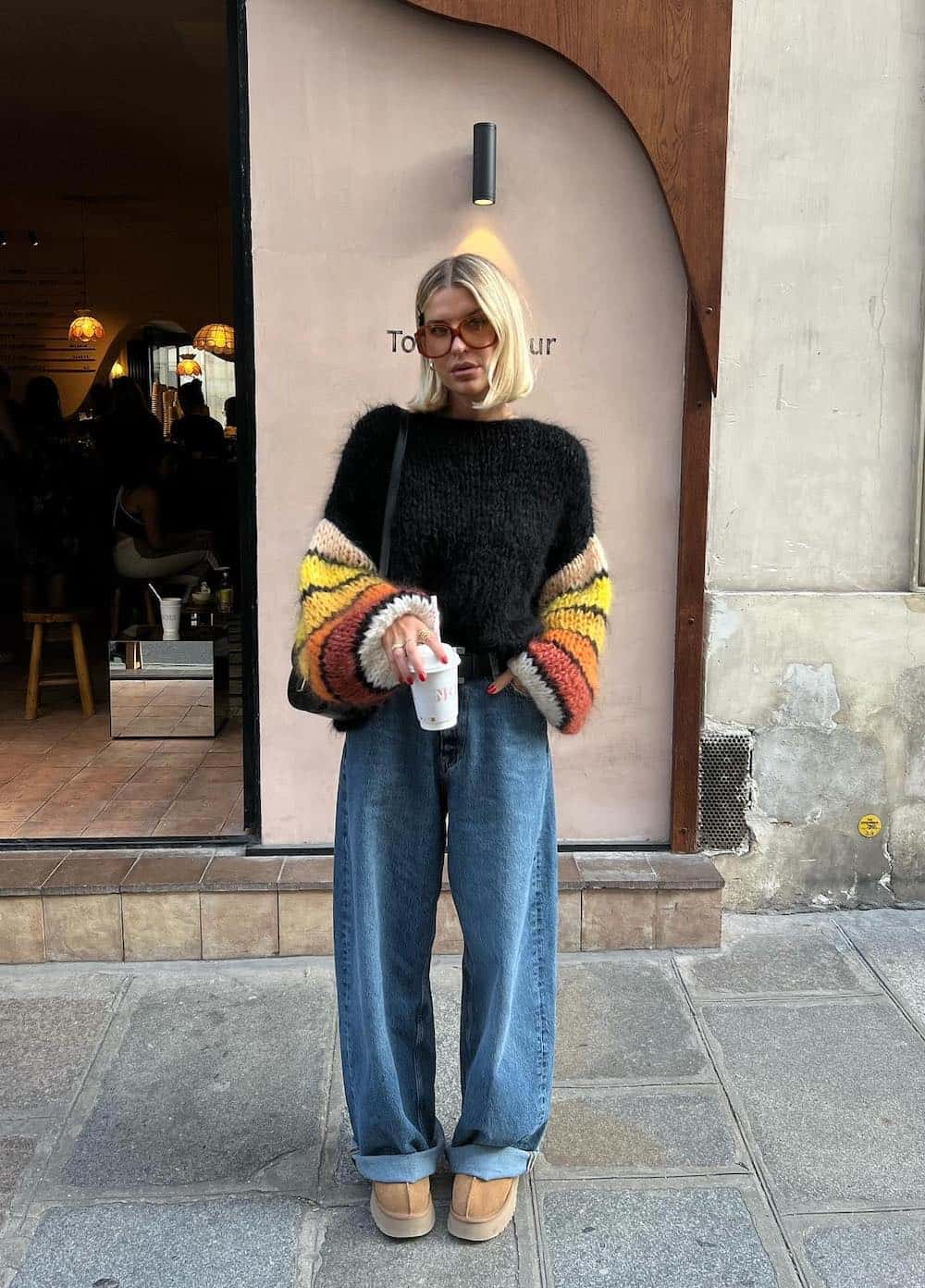 Woman wearing baggy jeans, Uggs and a color block sweater.