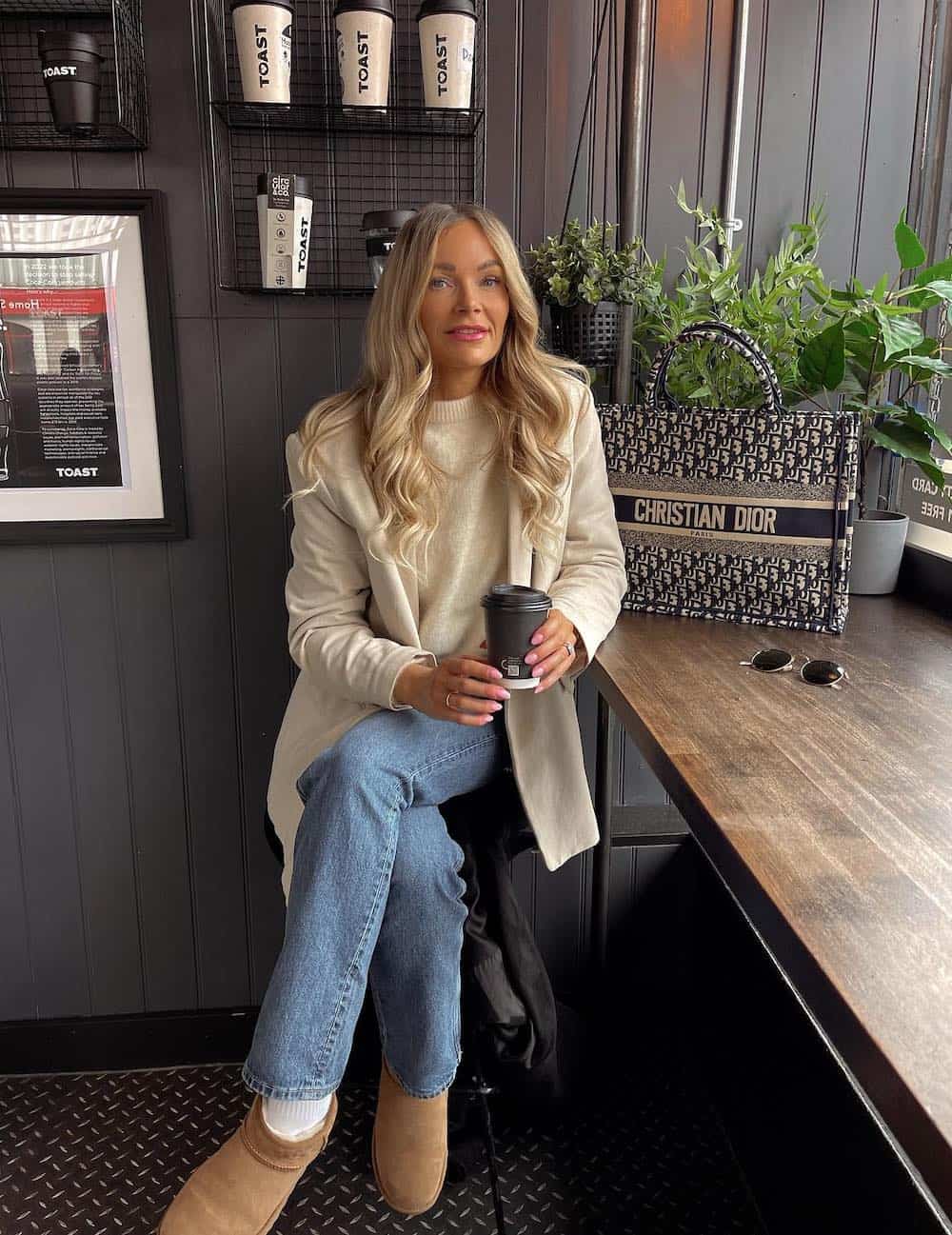 Woman wearing jeans, Uggs, a cream sweater and a cream cardigan.