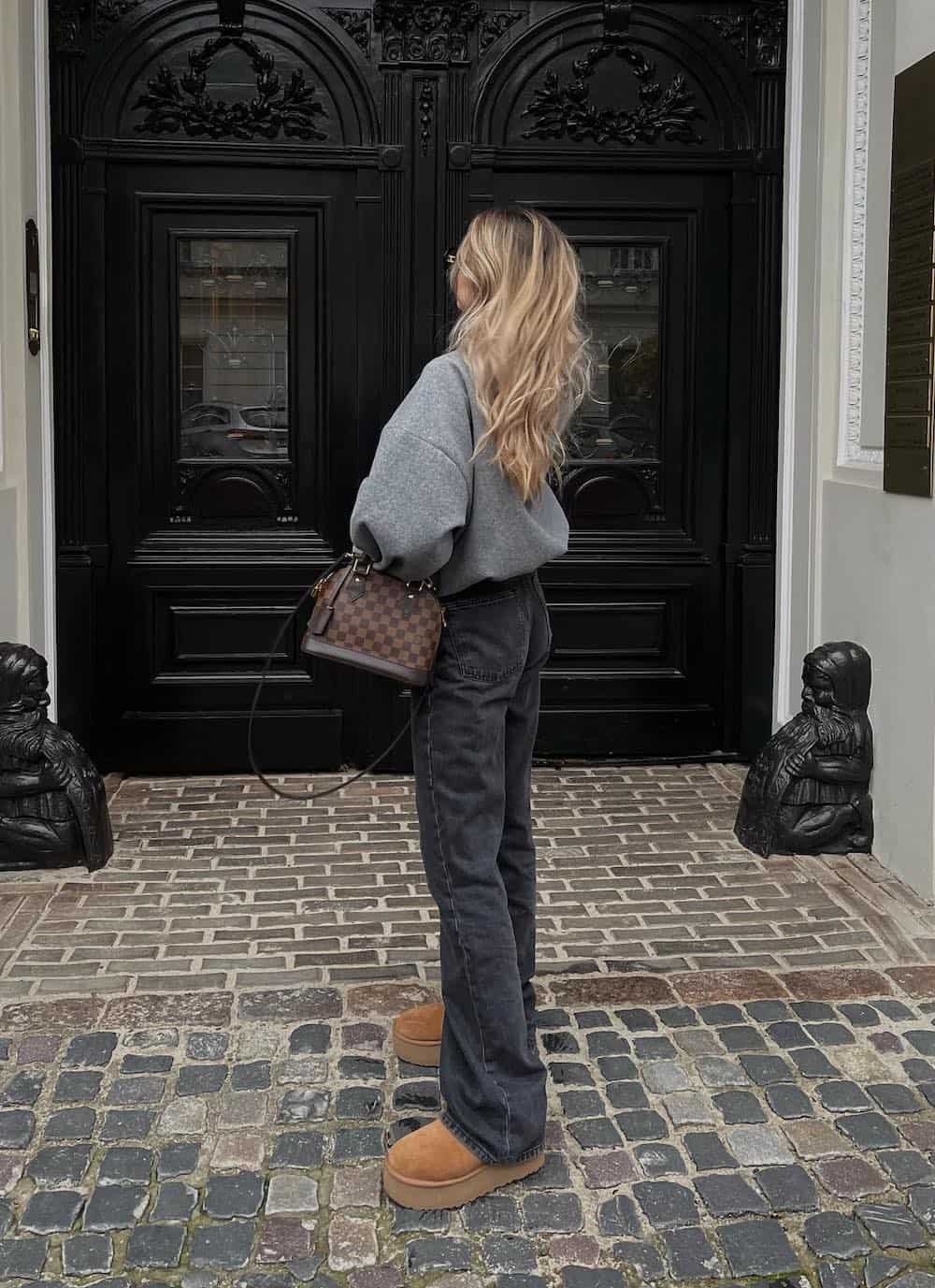 Woman wearing black jeans and a grey sweatshirt with Ugg boots.