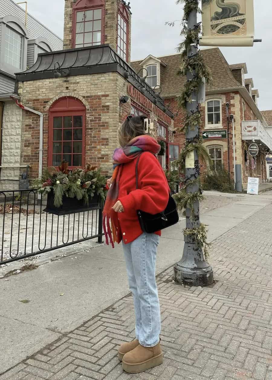 Woman wearing jeans, platform Uggs and a red jacket.