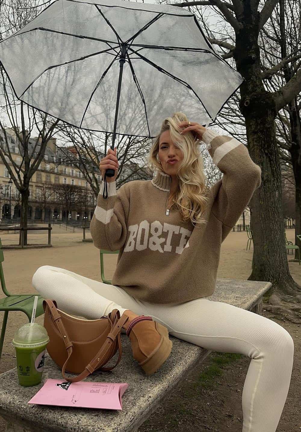 Woman wearing white leggings and a tan sweatshirt with Ugg boots.