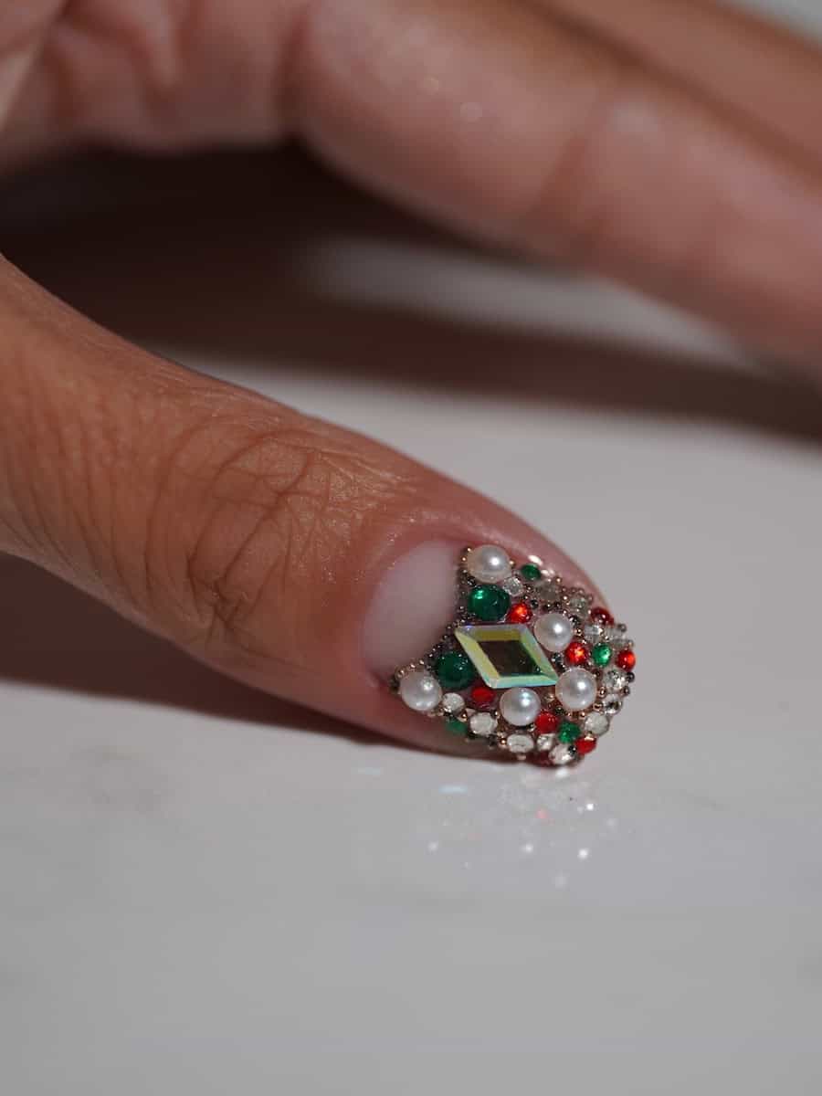 short nails covered with red, green, and white gems and pearls