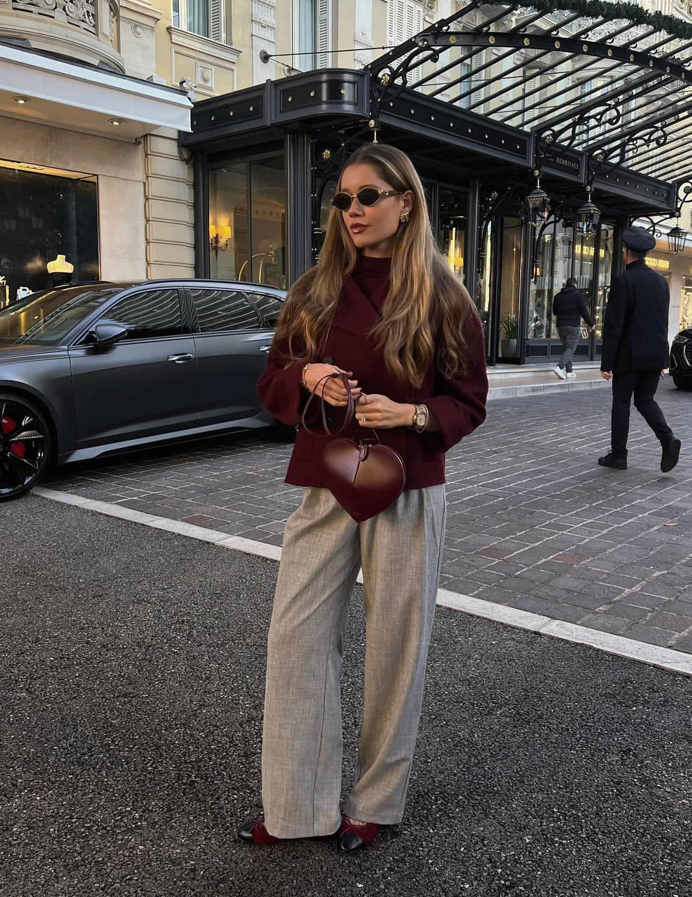 Woman wearing brown slacks, black and burgundy ballet flats and a burgundy coat.