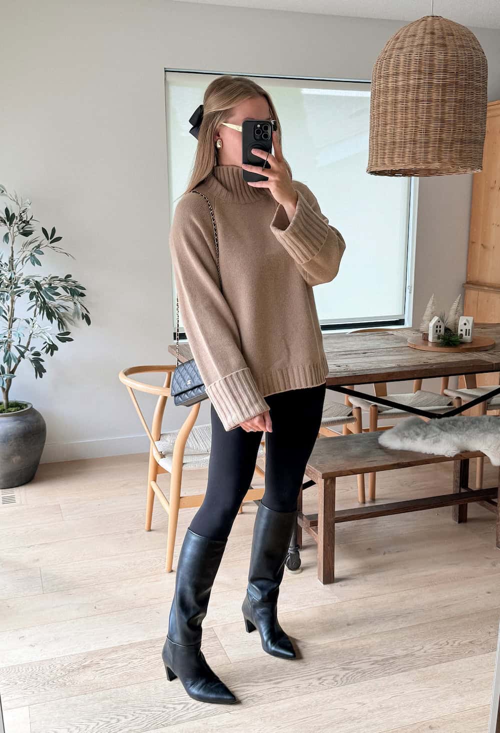 Christal wearing black leggings, a brown sweater and black cowboy boots.