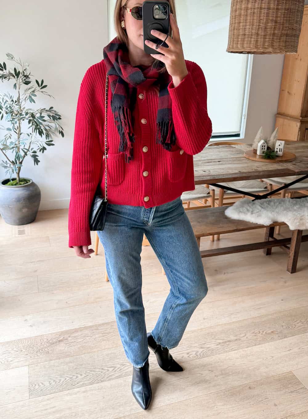 Christal wearing jeans, black booties, a red cardigan and a black and red scarf.