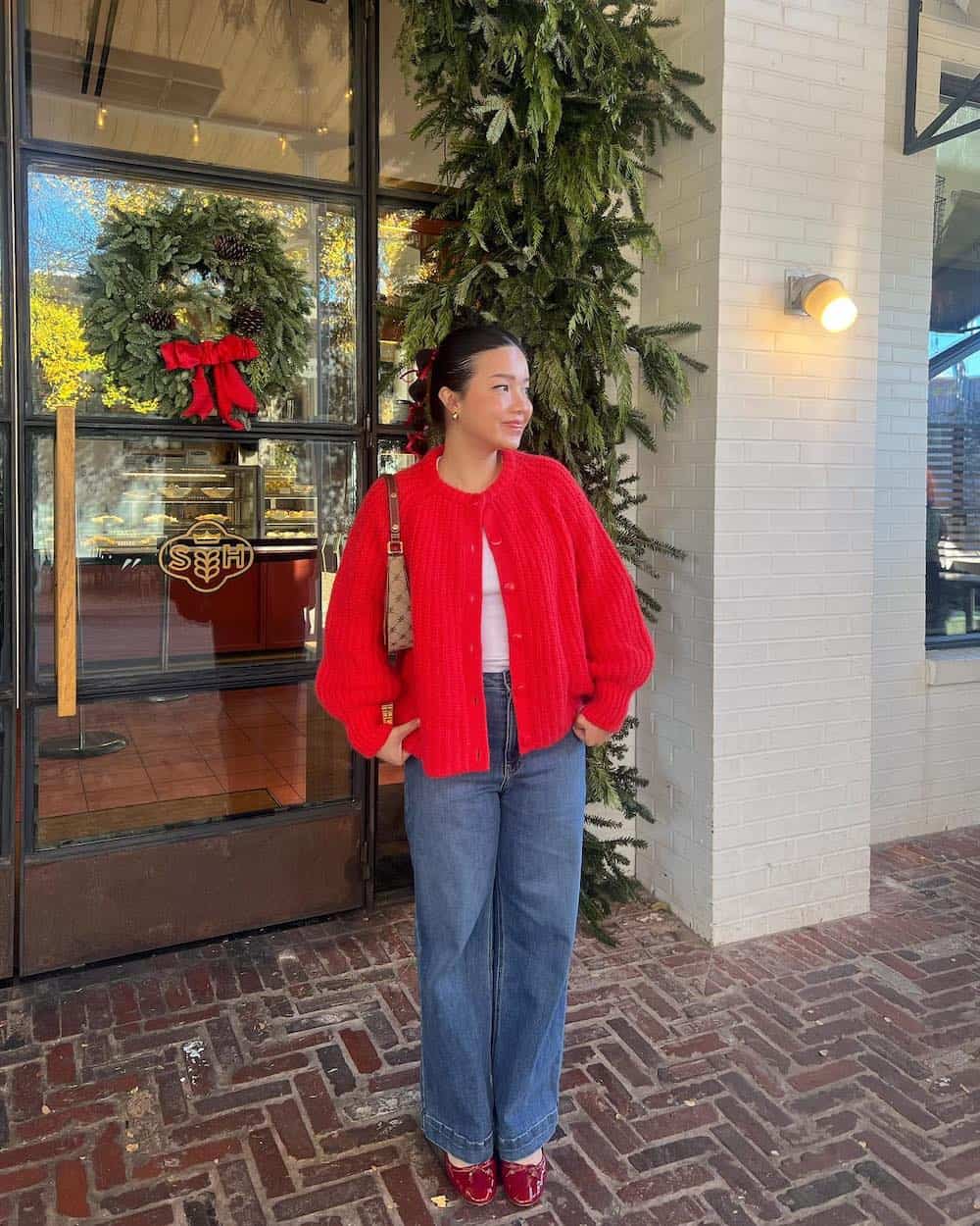 Woman wearing oversized jeans, red ballet flats a white t-shirt and a red oversized cardigan.