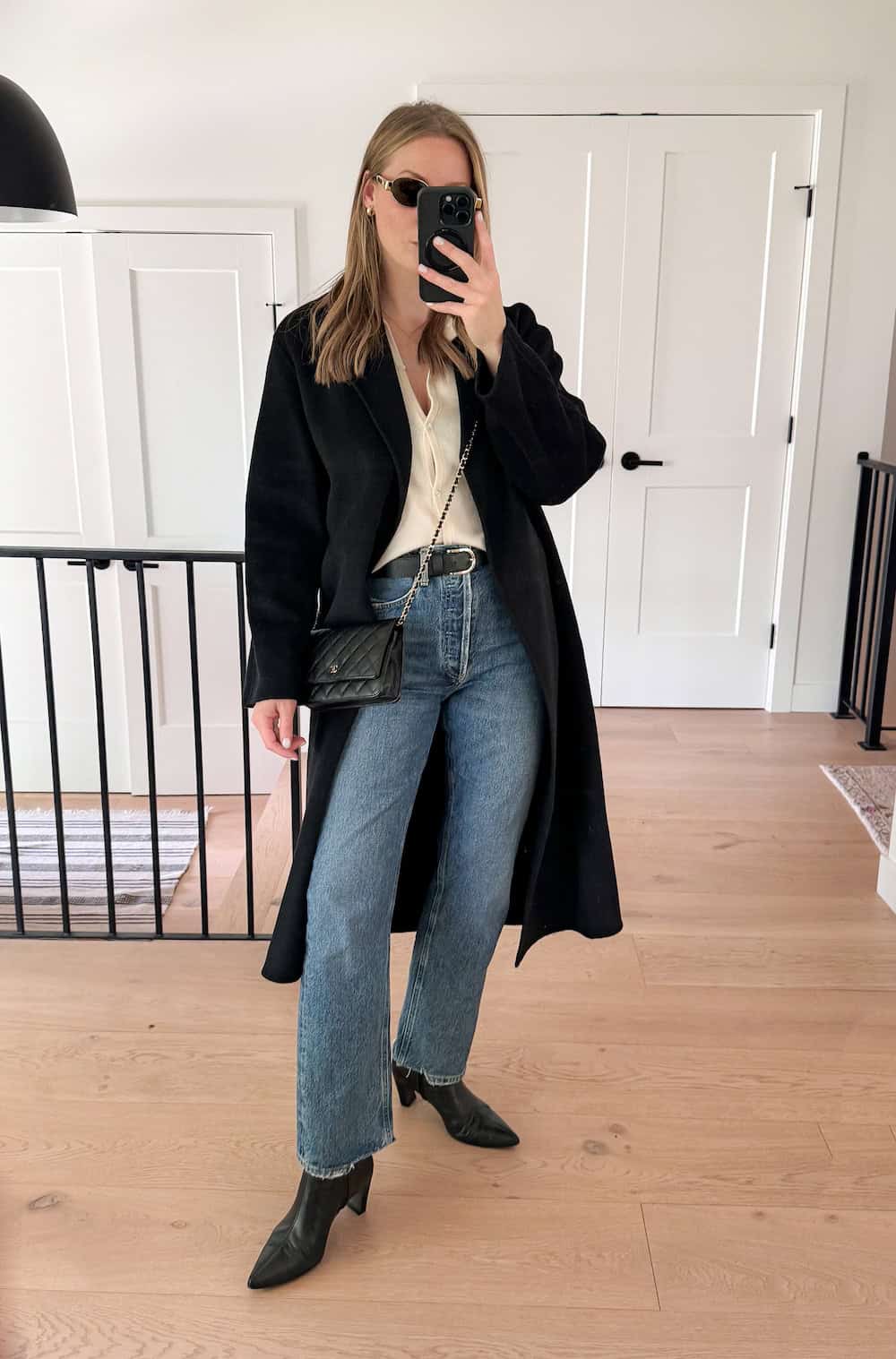 Christal wearing jeans, black booties, a button down and a long coat.