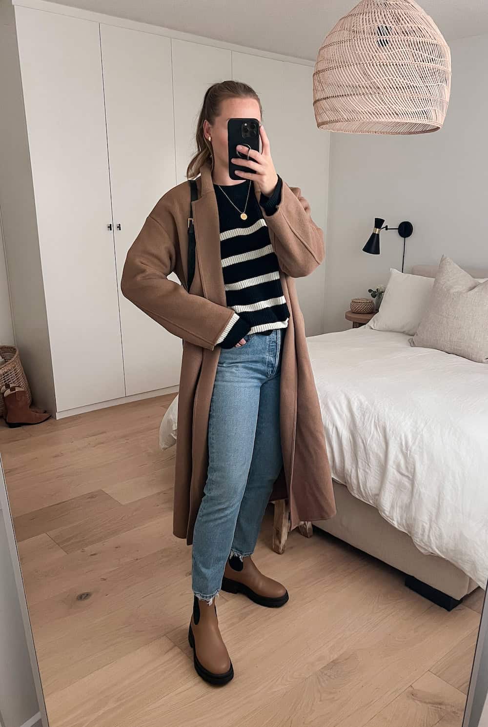 Christal wearing a black and white striped sweater with jeans, Chelsea boots and a long coat.