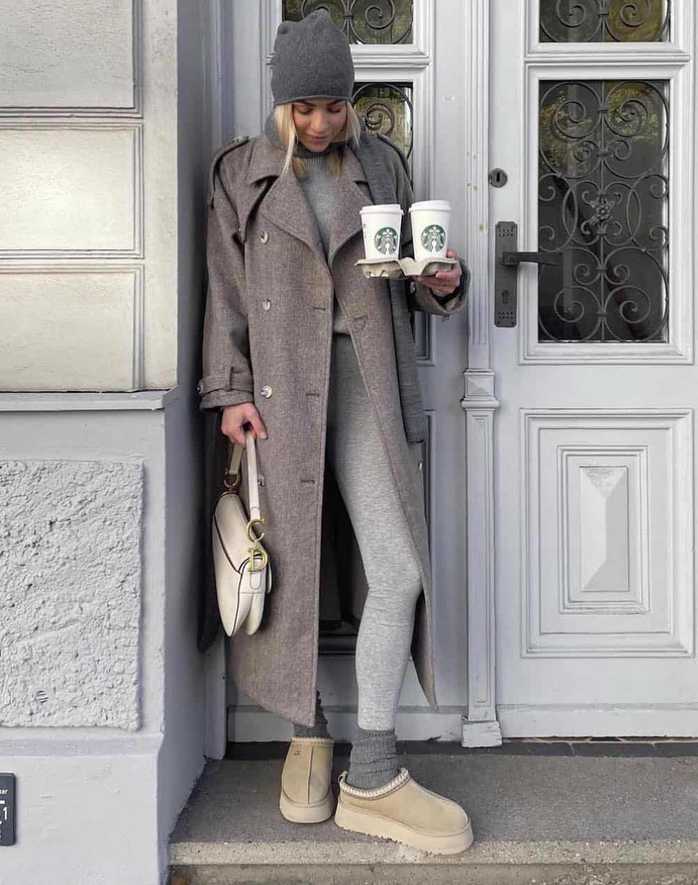 Woman wearing a long grey coat with grey leggings and Ugg boots.