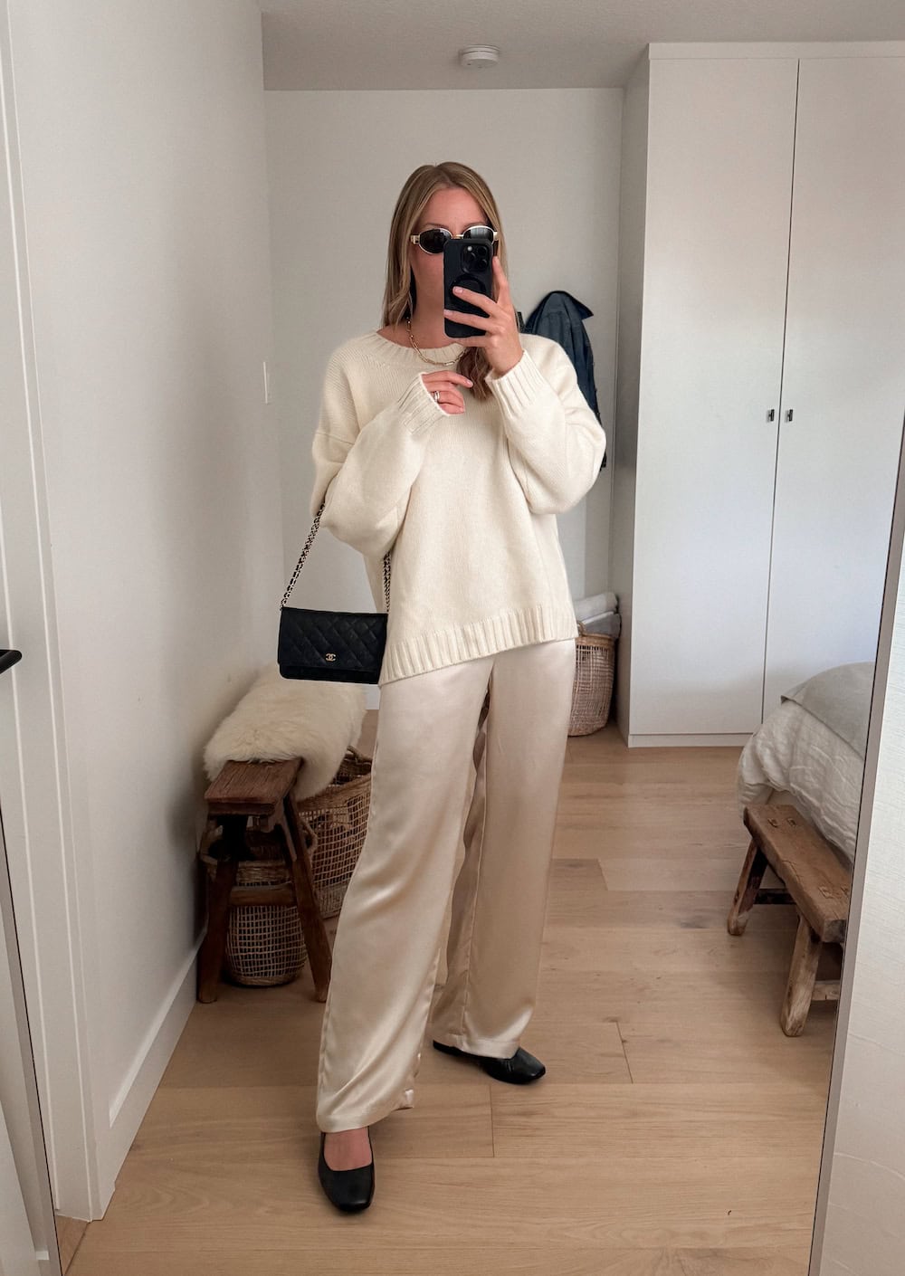 Christal wearing silk trousers with a white sweater and black ballet flats.