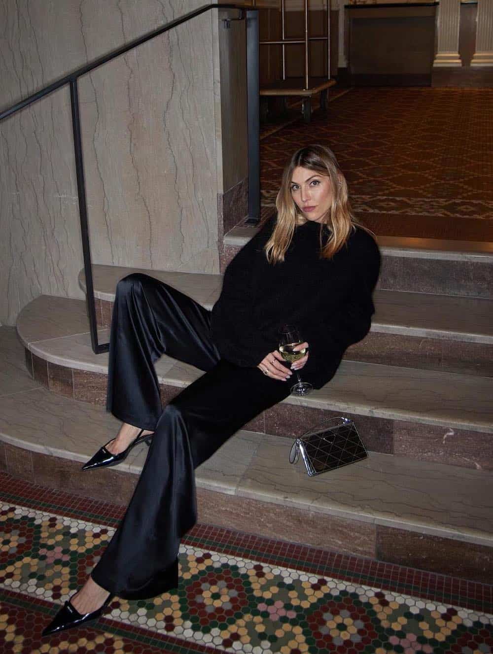 Woman wearing black silk trousers with a faux fur coat and slingback heels.