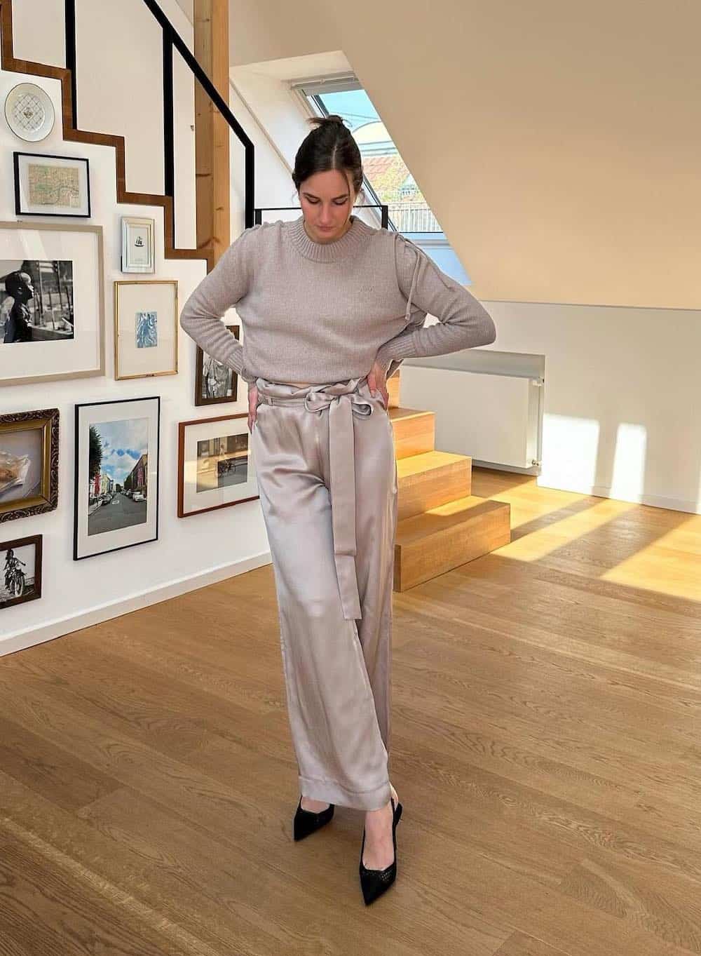 Woman wearing champagne colored silk paper bag pants with black sling back heels and a champagne colored sweater.